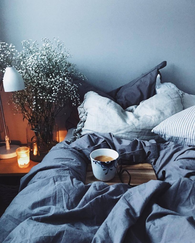 cosy home winter bed with cup of tea. Blue bedsheets